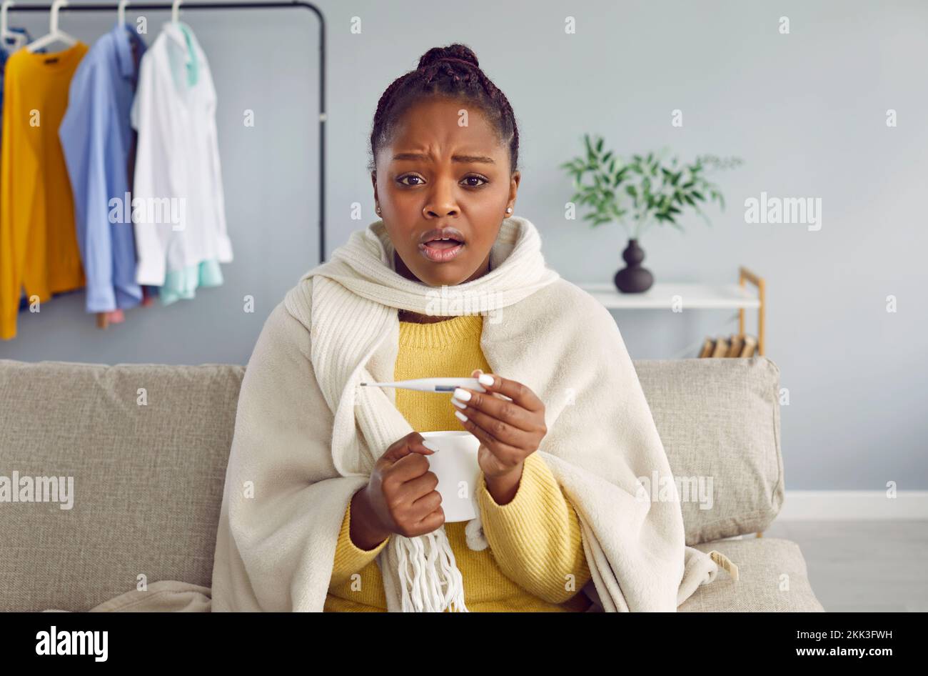 Mujer afroamericana joven que tiene frío y fiebre alta Foto de stock