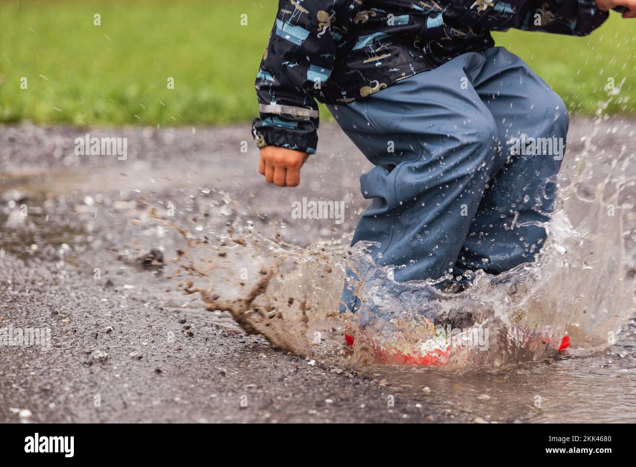 7 de octubre de 2020, Trebbin, una niña pequeña con zapatos de goma y medias  amarillas salta en un charco y tiene mucha diversión.