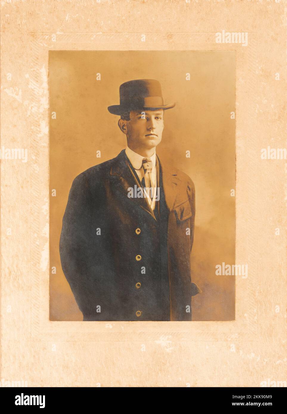 Antigua foto de tono sepia de un hombre joven de aspecto distinguido con traje y sombrero. Foto de stock