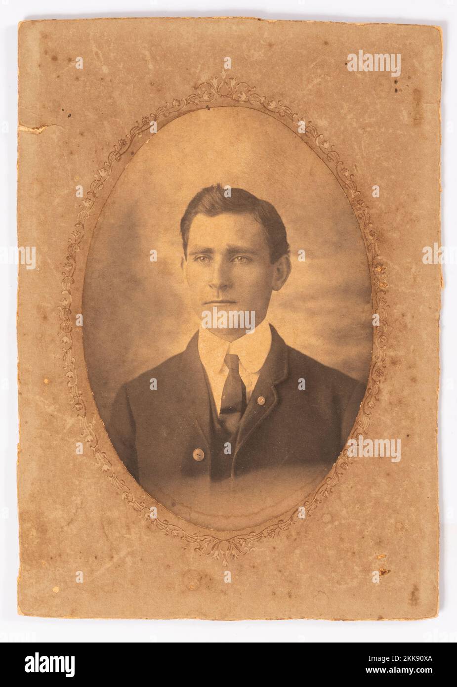 Foto antigua en blanco y negro de 1905 manchada y desteñida de un hombre joven. Enmarañado con recorte ovalado. Foto de stock