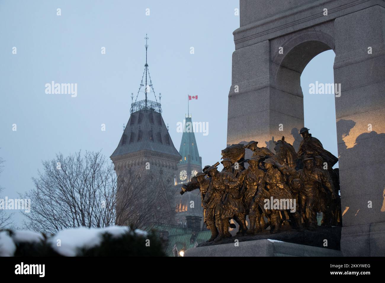 En una tarde nevada, se ve iluminado el Monumento Nacional a la Guerra en Ottawa, la capital de Canadá. La Torre de la Paz del Parlamento en el fondo lejano. Foto de stock