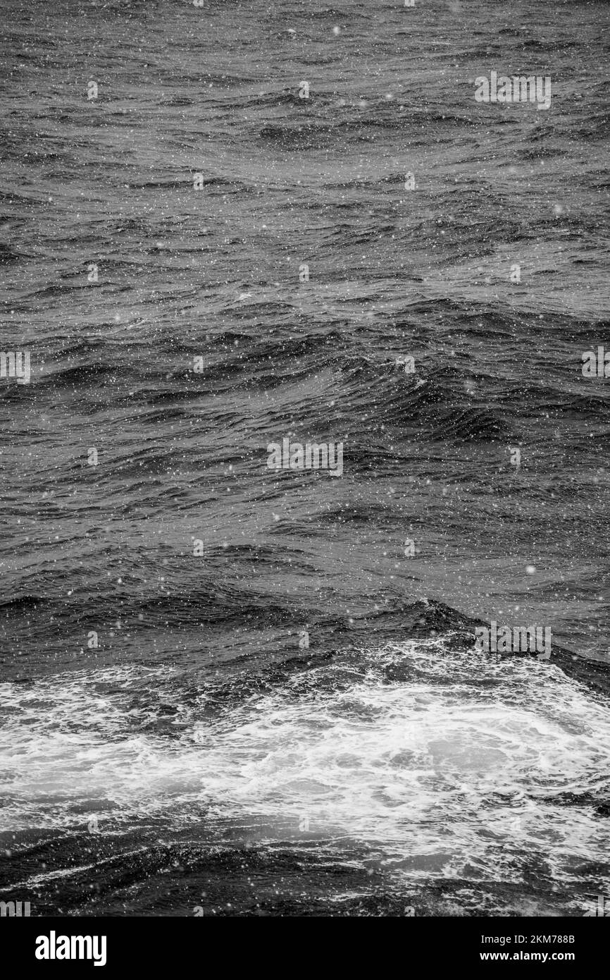 Imagen en blanco y negro de la nieve cayendo sobre el océano sur. Foto de stock