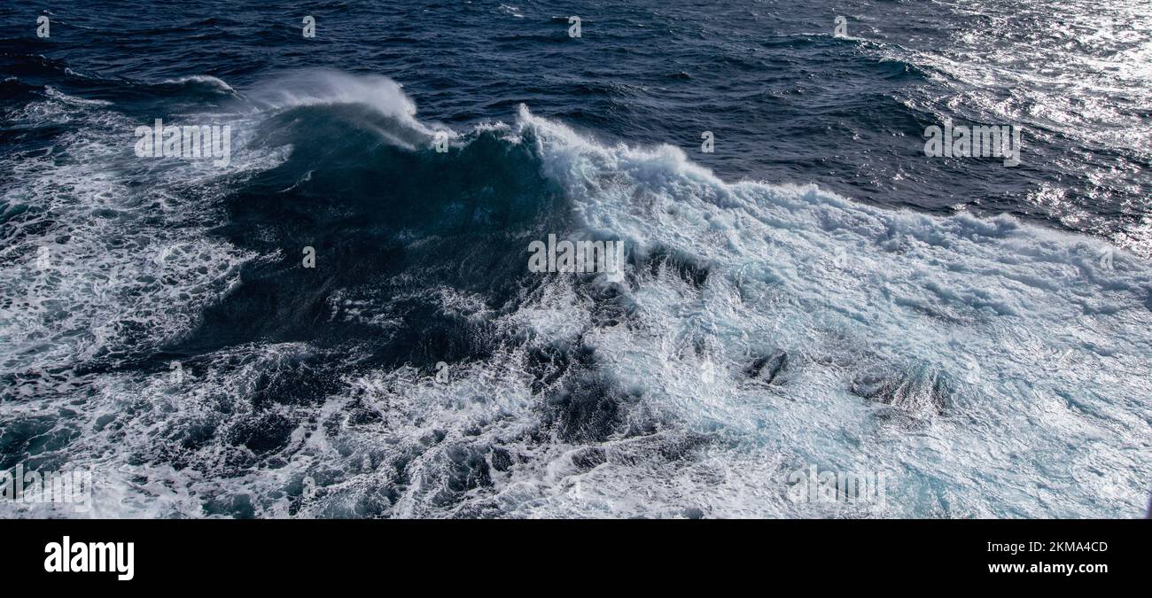 El barco despierta las olas en el Paso Drake, causando que el rocío salga del agua. Foto de stock