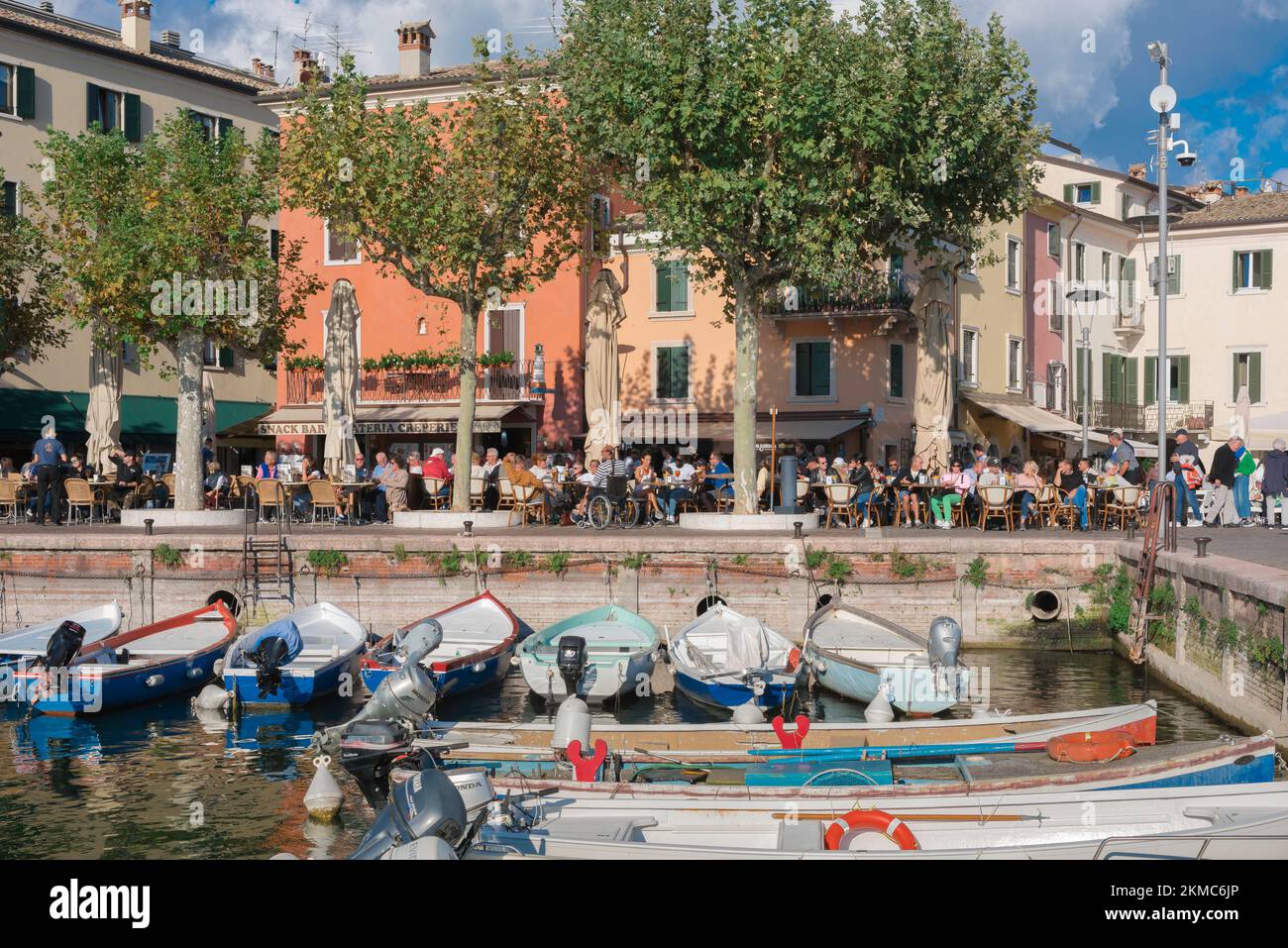 Garda Lago de Garda, vista en verano de las personas sentadas fuera de los cafés y bares en la Piazza Catullo en la zona costera de la ciudad vieja de Garda, Italia Foto de stock