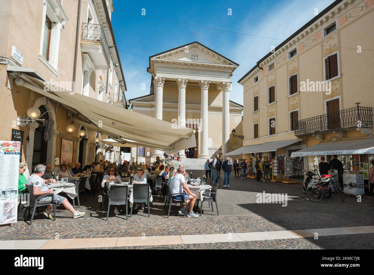 Ciudad de Bardolino Lago Garda, vista en verano de personas relajándose en mesas de café en Via San Martino en el centro histórico de la ciudad de Bardolino, Italia Foto de stock