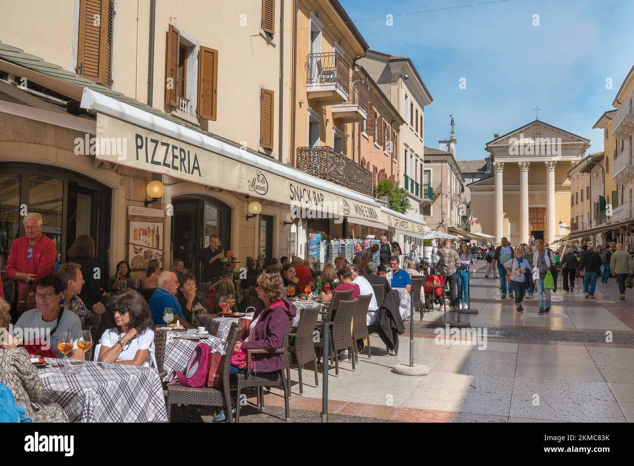 Ciudad de Bardolino Lago Garda, vista en verano de personas relajándose en mesas de café en Via San Martino en el centro histórico de la ciudad de Bardolino, Italia Foto de stock
