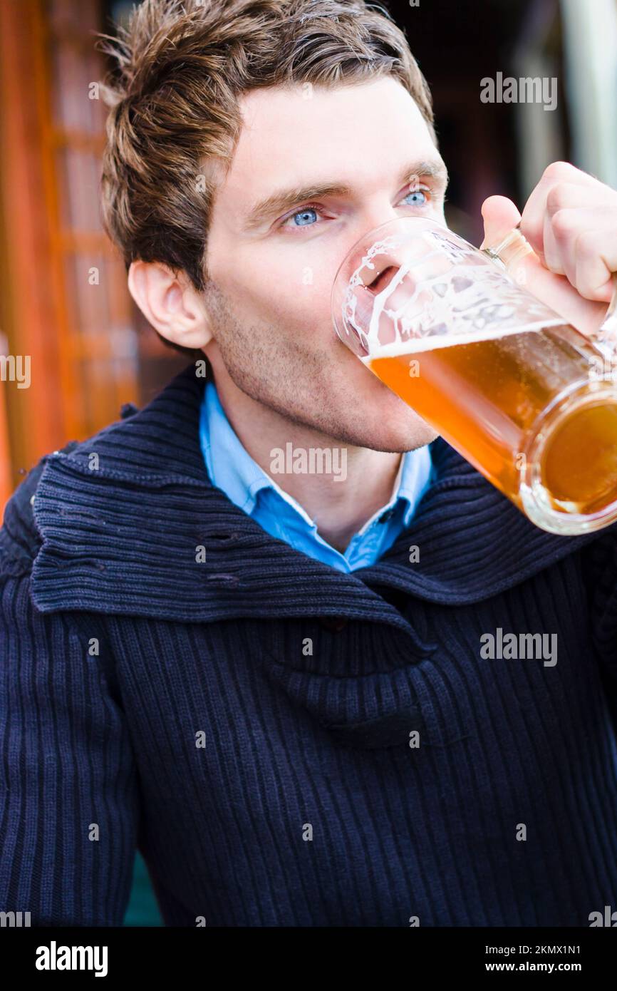 Inclinó la fotografía sin plantear de un hombre europeo disfrutando de una cerveza fría en un pub alemán mientras viajaba por Alemania para la Oktoberfest. Fotografía de viaje sincera Foto de stock