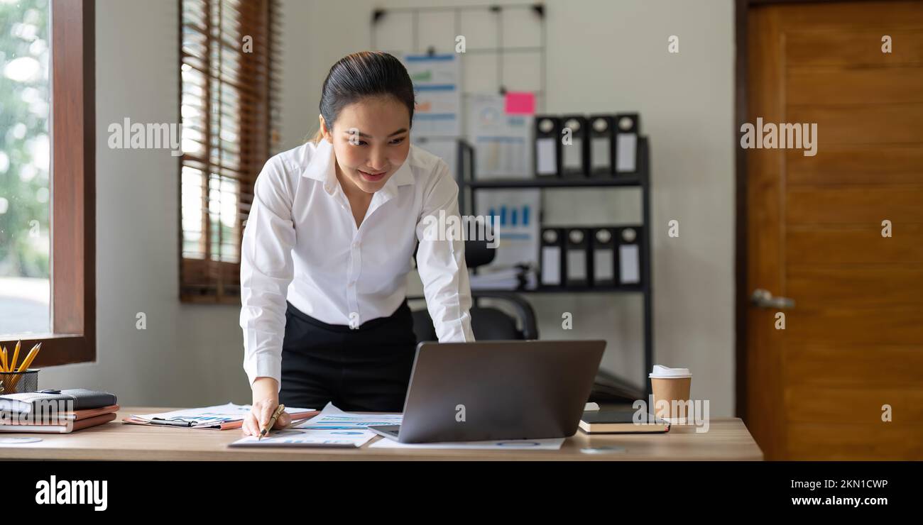 Hermosa mujer de negocios de Asia utilizando en el portátil para el análisis financiero. Foto de stock