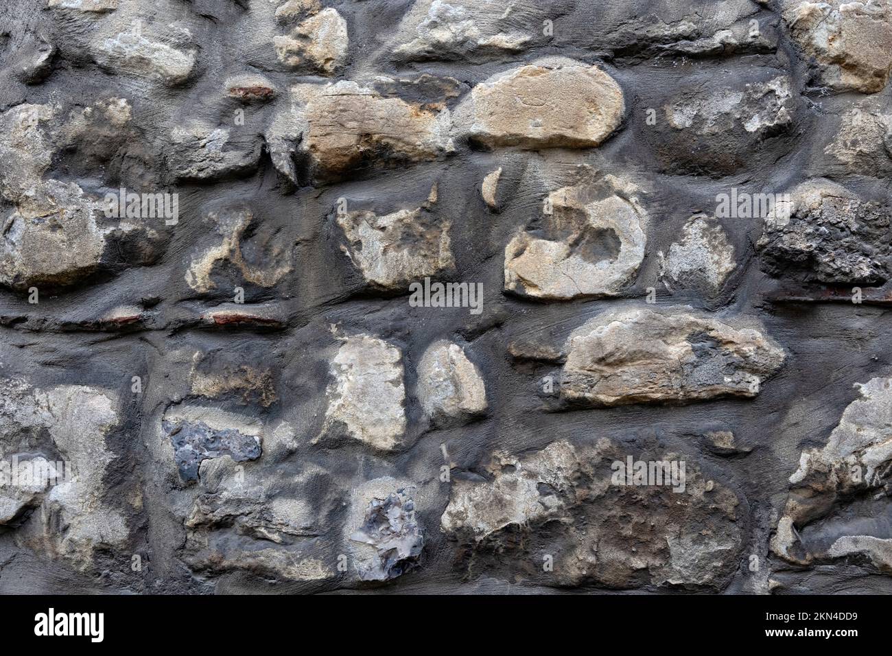 Textura de fondo de la pared construida de piedras oscuras de forma irregular Foto de stock