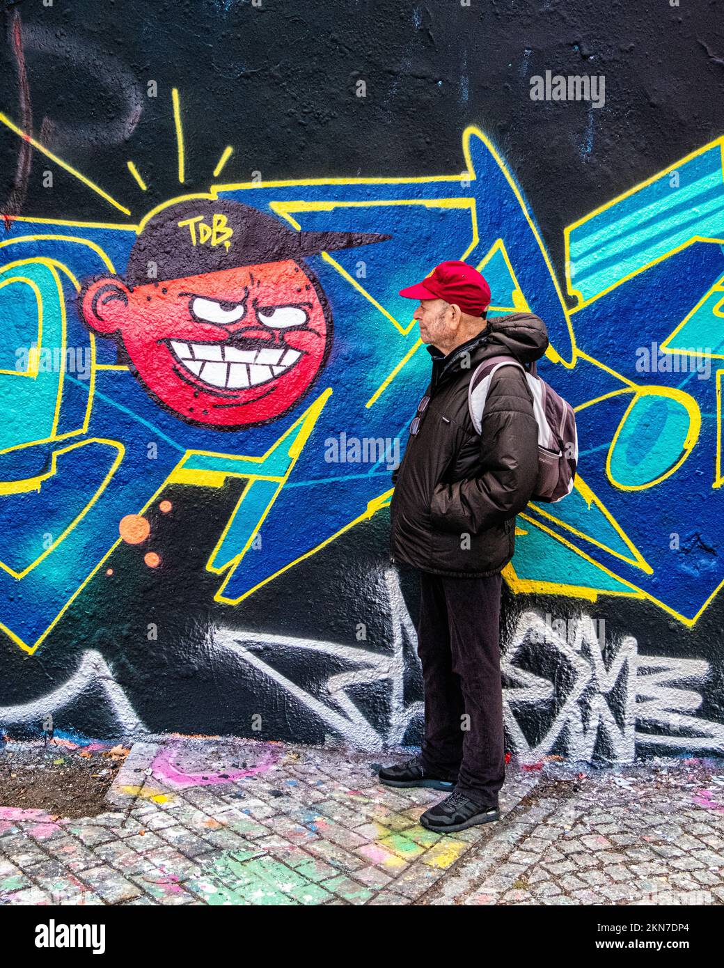 El hombre mayor mira a la pared de arte de la calle en Mauer Park, Prenzlauer Berg,Berlín,Alemania.Esta galería en constante cambio era parte del Muro de la Frontera de Berlín Foto de stock