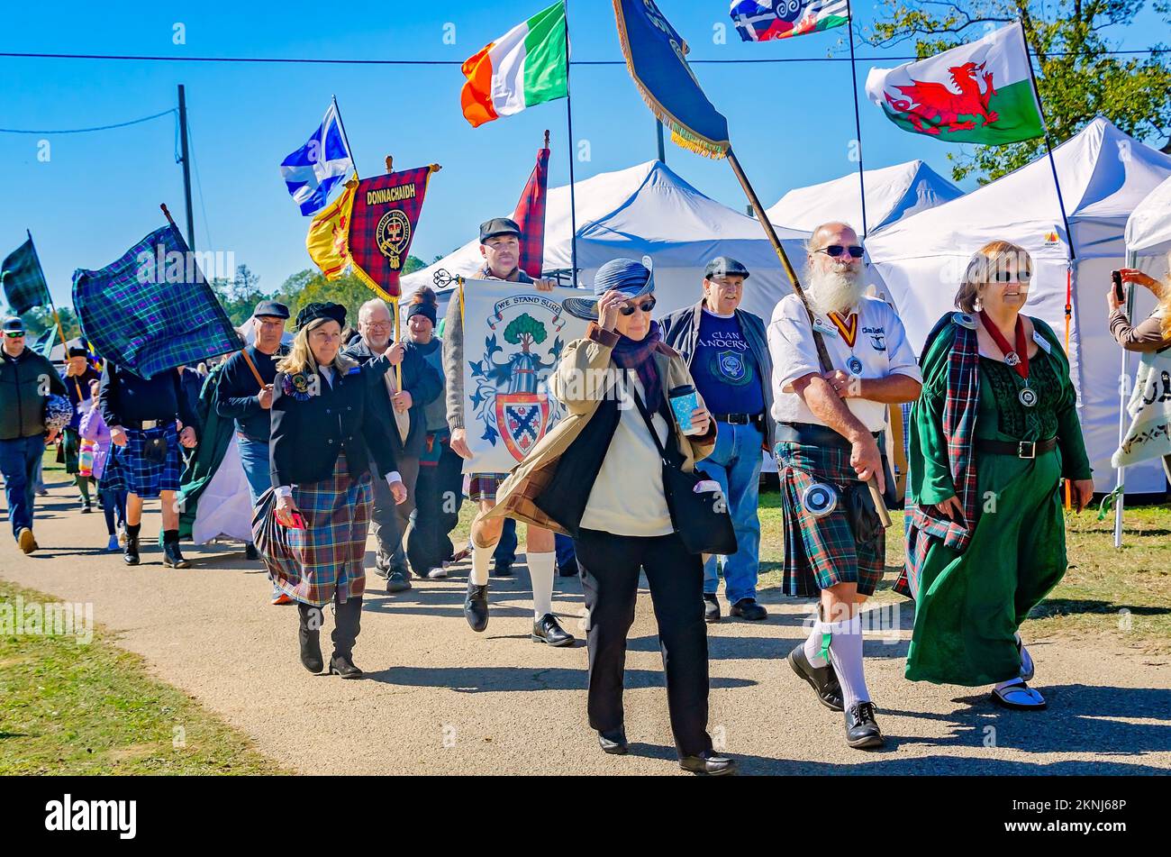 La gente lleva pancartas de tartán y banderas celtas durante el desfile de los tártanes del clan en los Juegos Escoceses de las Tierras Altas en Gulfport, Mississippi. Foto de stock
