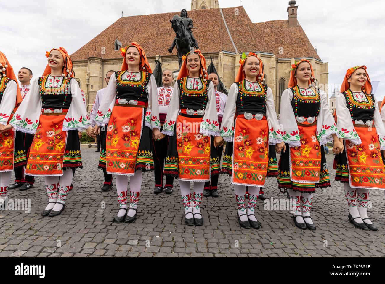 Bailarines folclóricos rumanos y húngaros frente a la Iglesia de San Miguel en la Plaza Unirii, Cluj-Napoca, Rumania Foto de stock