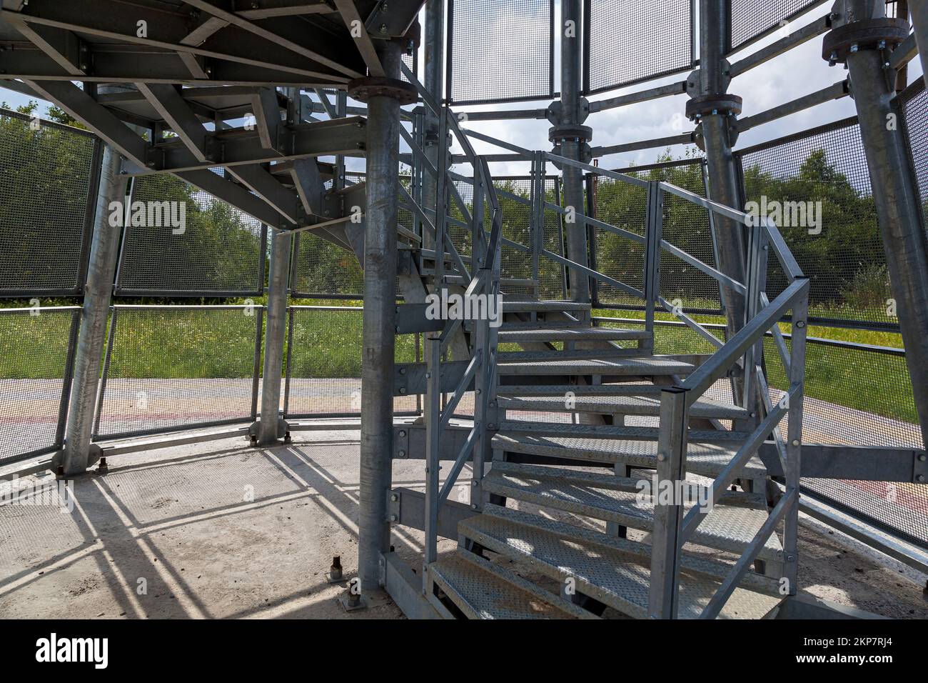 Estructuras metálicas de una escalera de caracol en la plataforma de observación, cercada con una rejilla metálica. Foto de stock