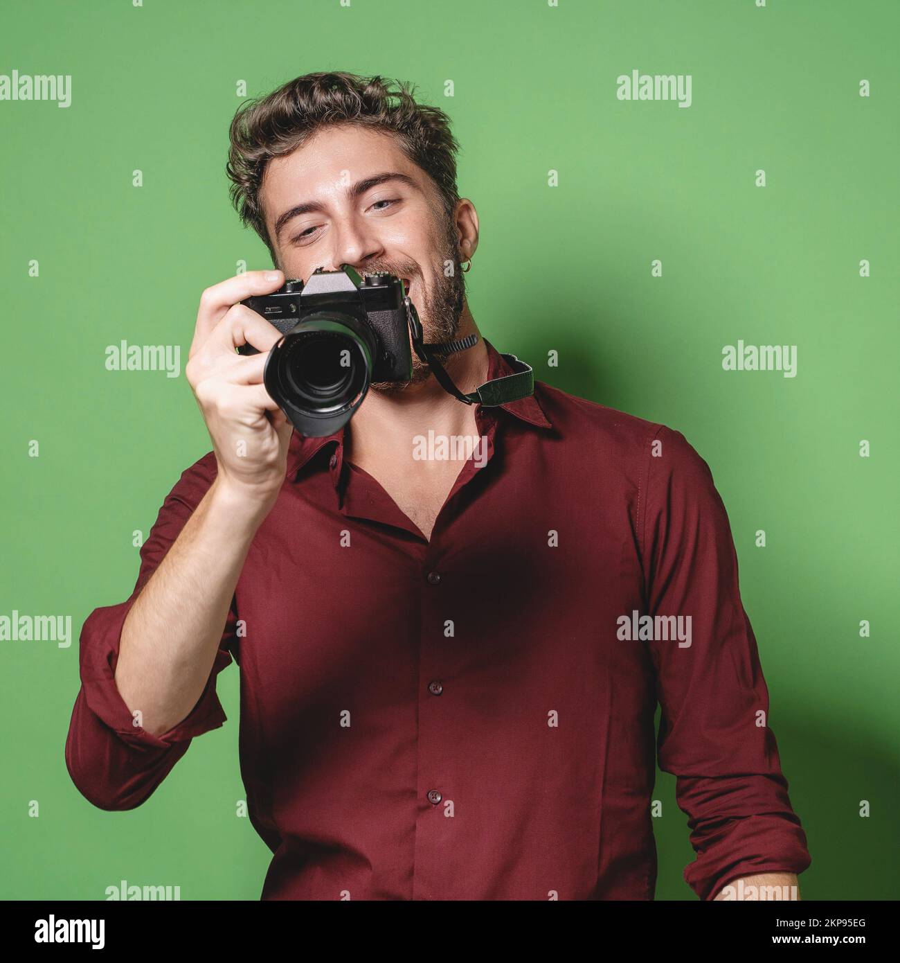 Fotógrafo guapo y de moda que revisa las imágenes de la pantalla digital de  una cámara sin espejo - estudio grabado - aislado sobre fondo verde  Fotografía de stock - Alamy