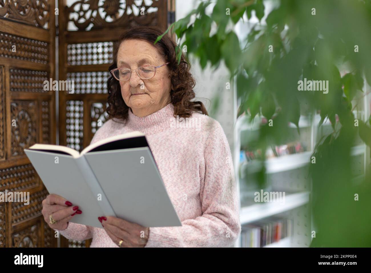 Mujer anciana caucásica leyendo un libro. Pasatiempos y entretenimiento para jubilados. Foto de stock
