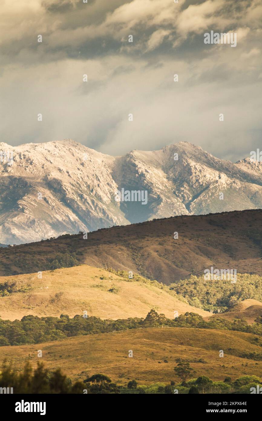 Tasmania Paisaje en la meseta de terreno montañoso enmarcado con llanuras de pasto y cielos nublados. Cordillera de la costa oeste, Tasmania occidental, Australia Foto de stock