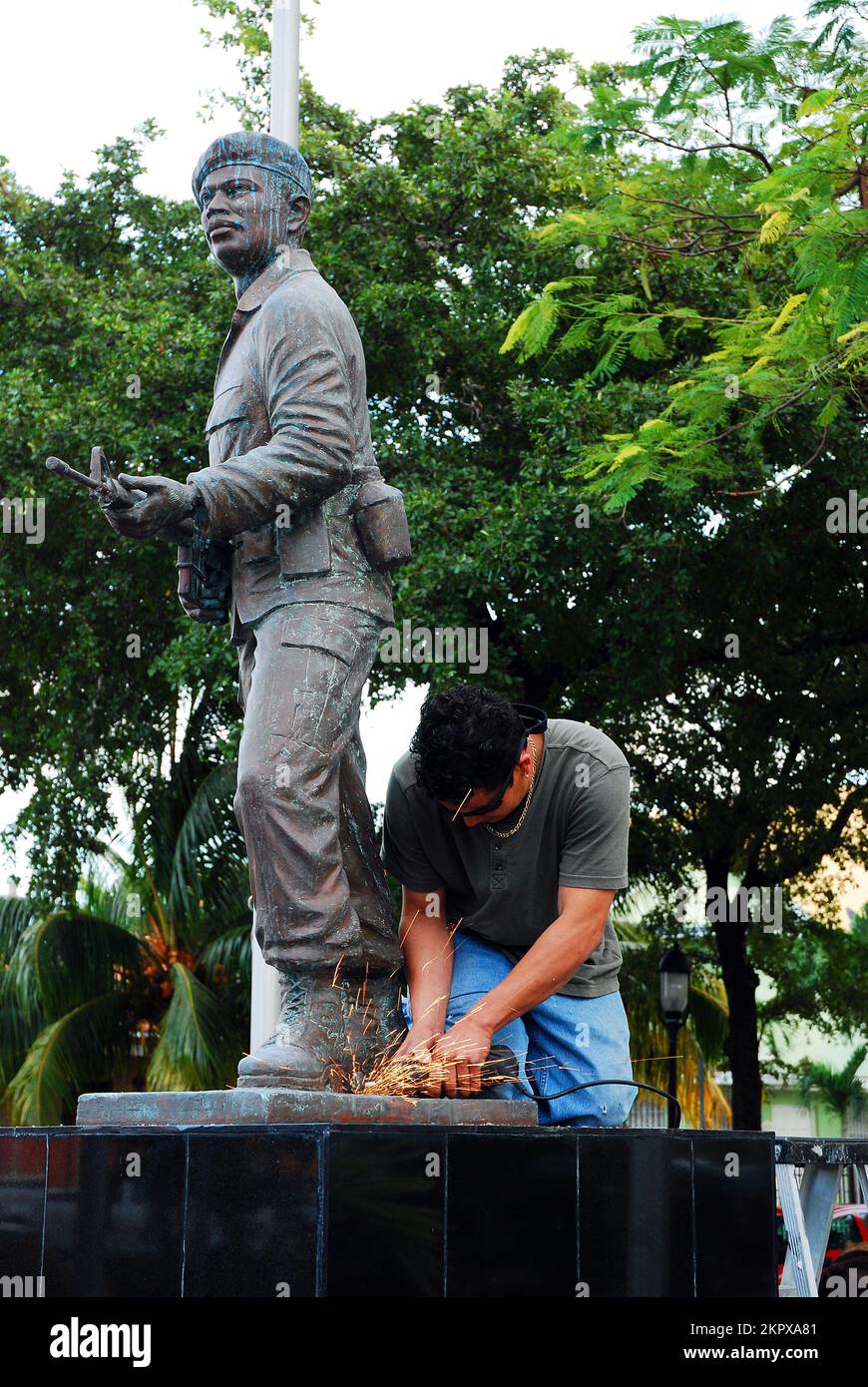 Un trabajador lidia la suciedad y la mugre en una estatua que rinde homenaje a Nestor Antonio Izquierero en Miami Foto de stock