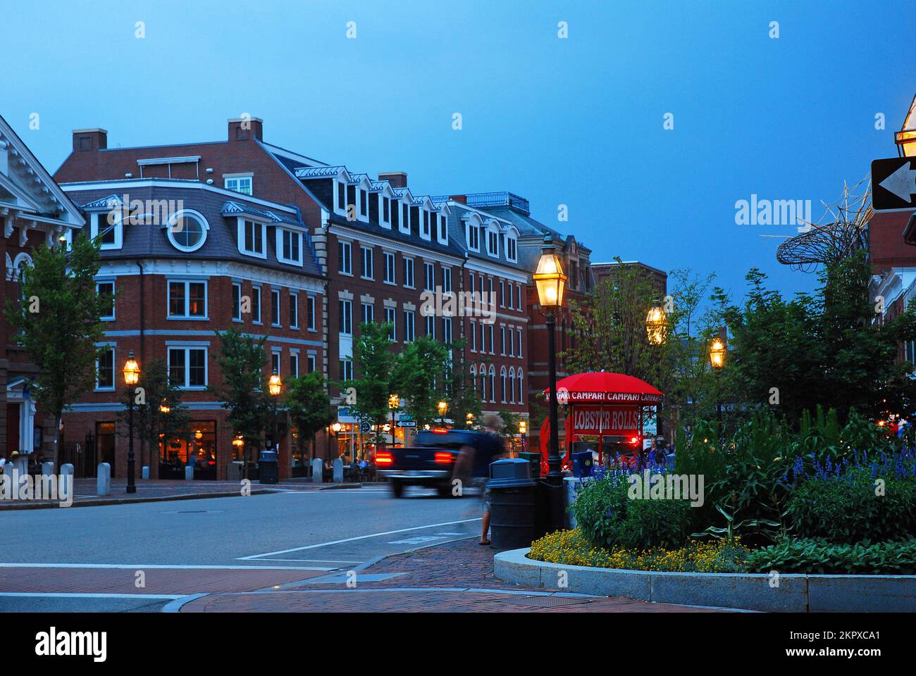 Las luces de las calles se encienden al anochecer, iluminando la tienda y los restaurantes del centro de Portsmouth, New Hampshire Foto de stock