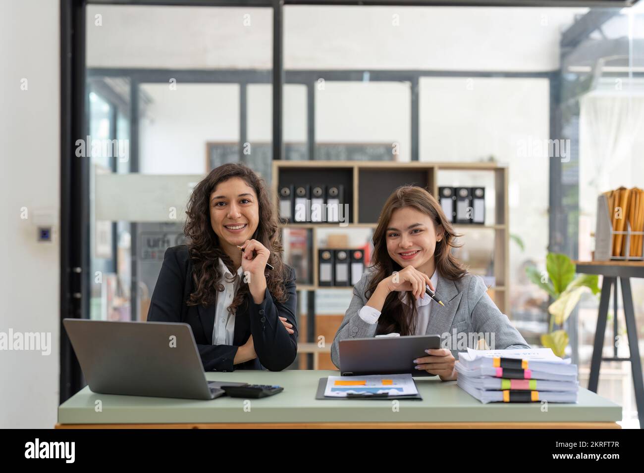 Retrato de dos felices y amistosos profesionales multiétnicos, alegres socios de negocios de éxito colegas en la oficina Foto de stock