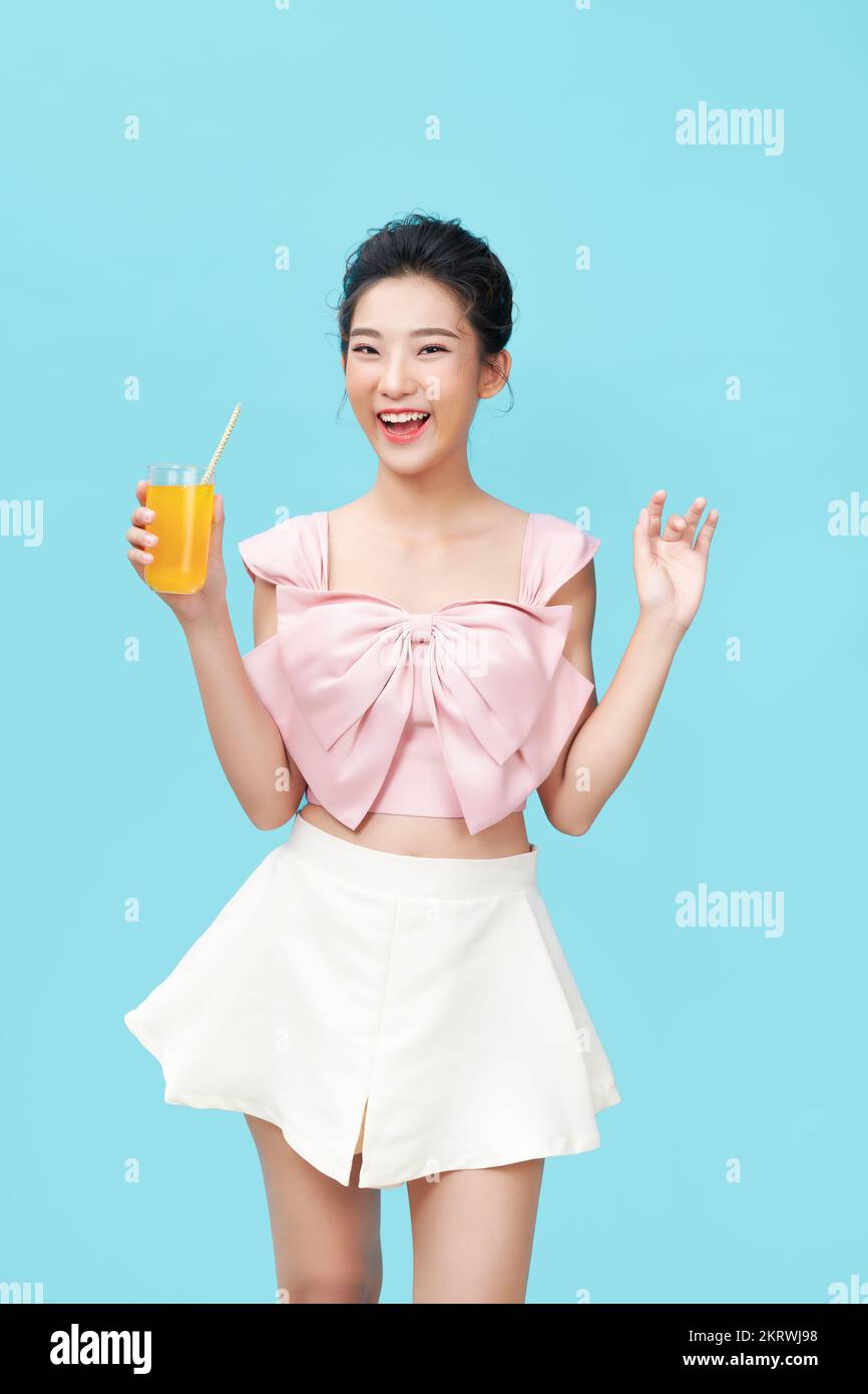 Retrato de una joven feliz bebiendo jugo de naranja durante el desayuno. Foto de stock