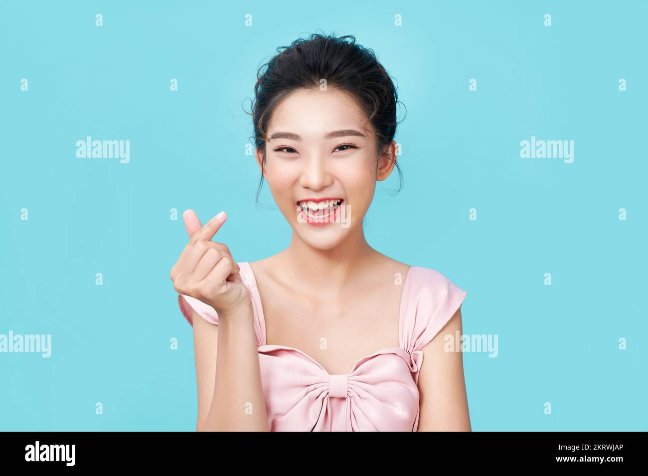 Joven feliz romántico afectuoso asiático forma mini gesto de corazón con los dedos demostrando un signo de amor Foto de stock