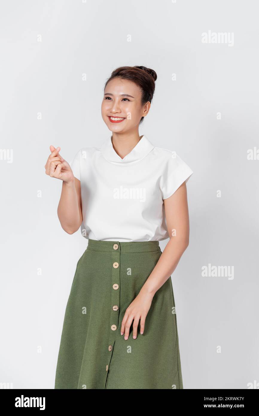 Mujer joven asiática que muestra mini signo de corazón aislado sobre fondo blanco Foto de stock