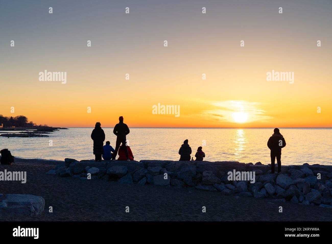 Un grupo de espectadores de la silueta observa el amanecer en Leuty Beach, Toronto Foto de stock