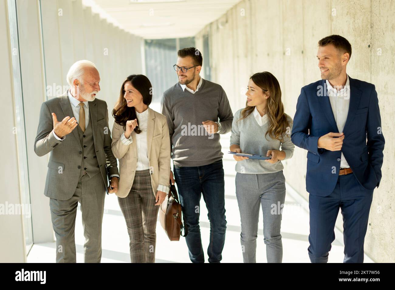 Grupo de profesionales de negocios corporativos caminando por el corredor de oficinas en un día soleado Foto de stock