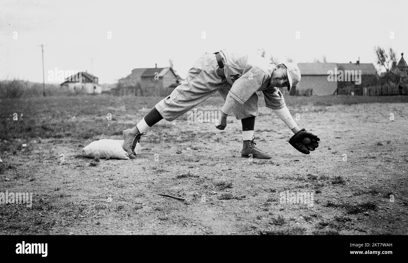 1934, histórico, fuera en un campo de tierra, un colegial con equipo de béisbol de la época, con un guante de béisbol apoyado para atrapar una pelota, Mapplewood Grammar School, EE.UU. Foto de stock