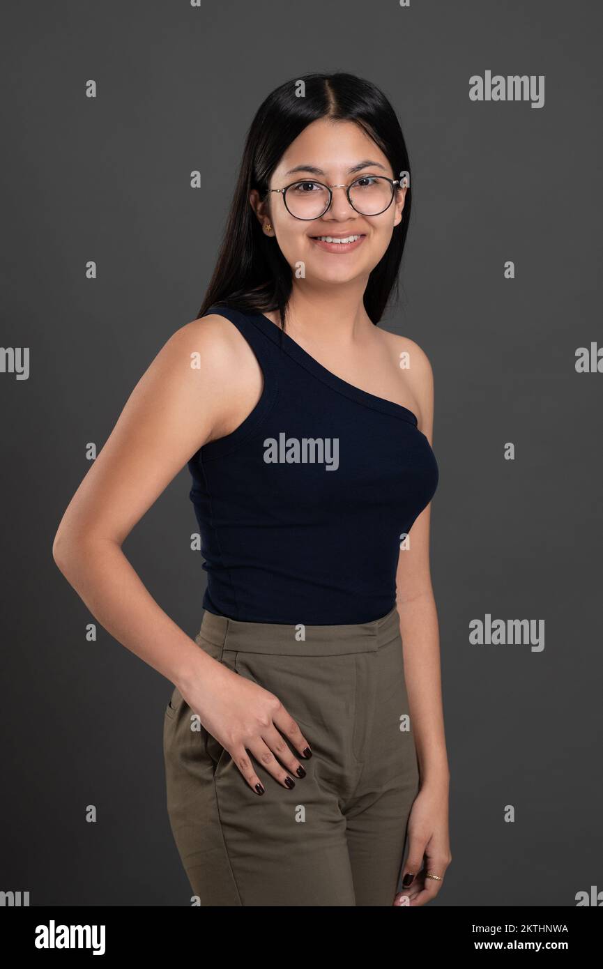 Bonito retrato de una chica latina en gafas aisladas sobre el fondo del estudio Foto de stock