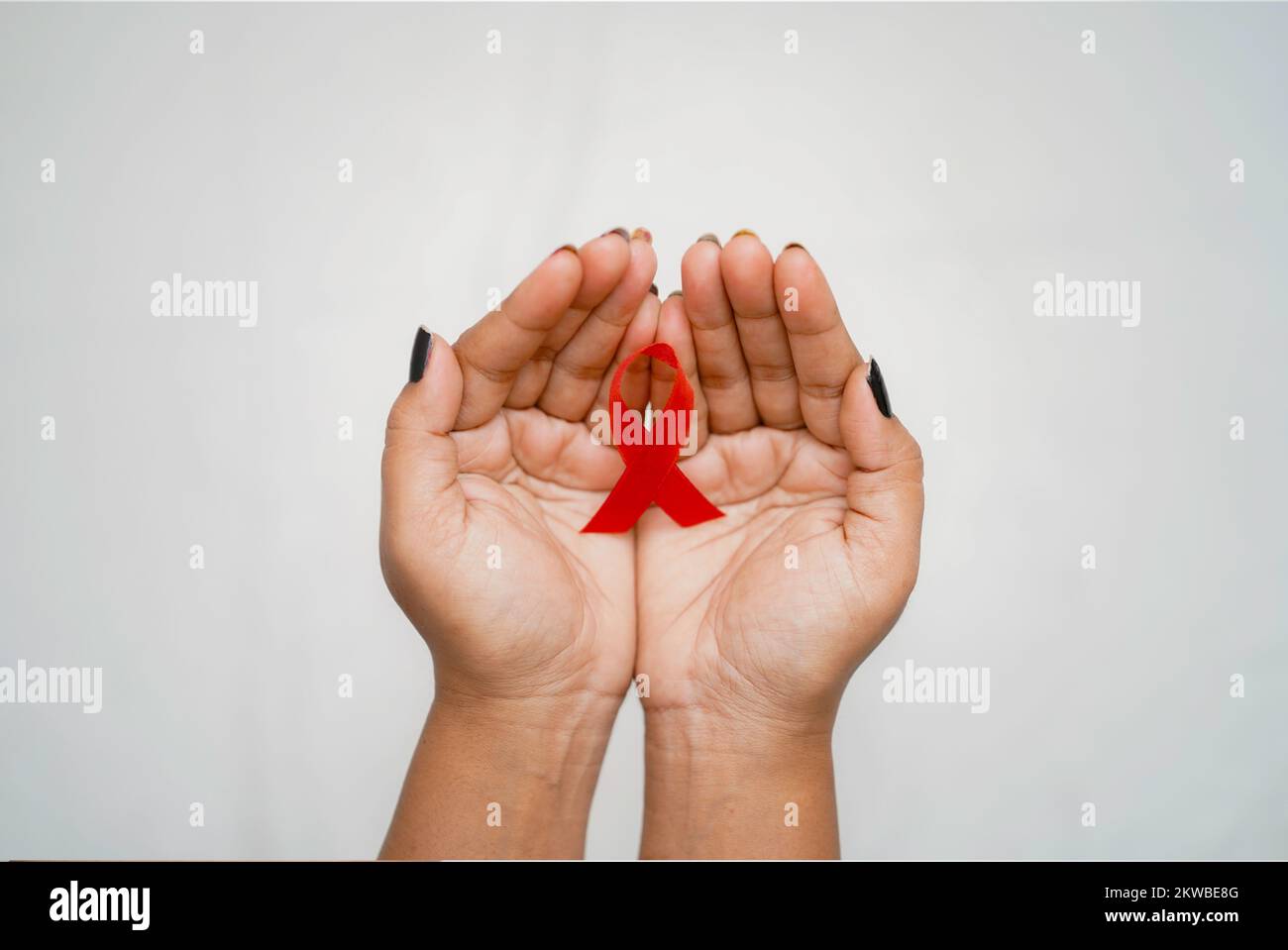 El Día Mundial del VIH/SIDA, Una vista superior Primer plano Manos  sosteniendo una cinta roja de concienciación sobre el fondo blanco Concepto  del Día Mundial del SIDA Fotografía de stock - Alamy