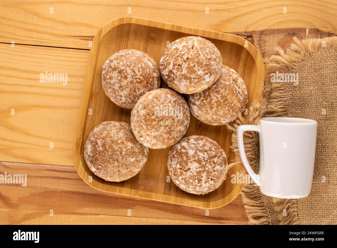 Varias galletas dulces y deliciosas de jengibre con plato de bambú y taza blanca sobre mesa de madera, macro, vista superior. Foto de stock