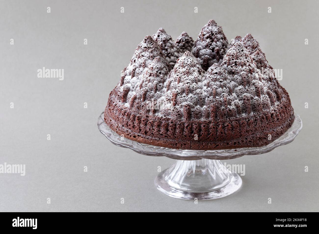 Un pastel de chocolate navideño. La torta se hace usando un molde de bundt para formar la masa de la torta en las formas del árbol. Una aspersión de azúcar glaseado lo cubre. Foto de stock