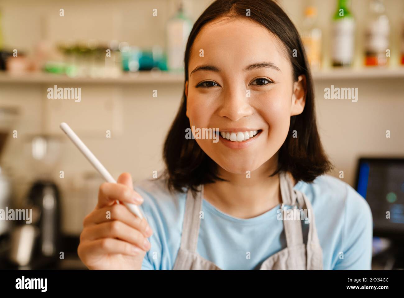 Joven camarera asiática que trabaja con la tableta en el café Foto de stock