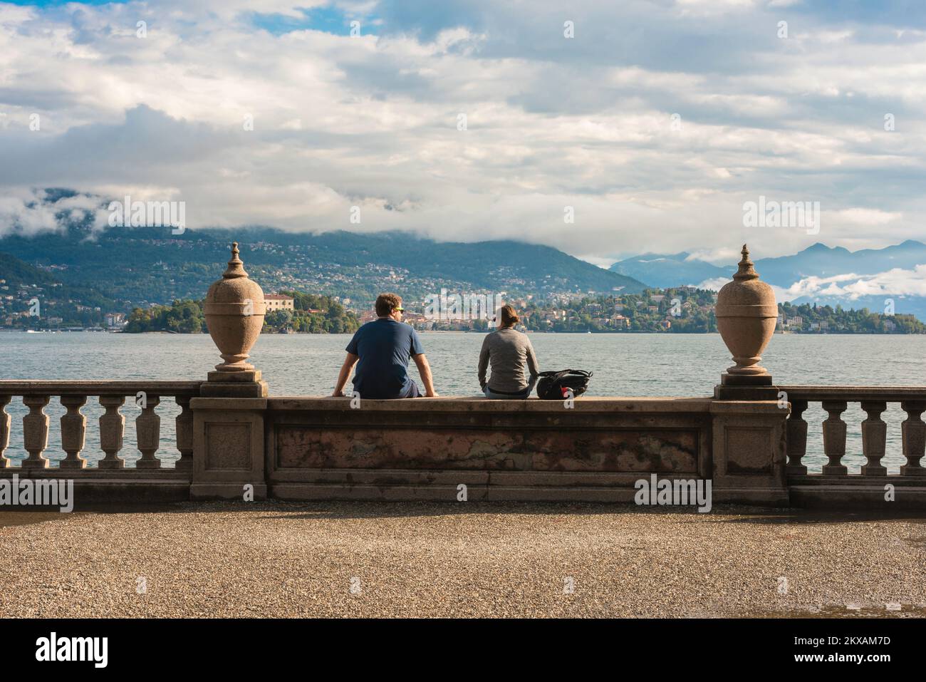 Pareja de viaje, vista trasera de un joven y una mujer sentados juntos en los terrenos del Palazzo Borromeo, Isola Bella, Lago Maggiore, Italia, Europa Foto de stock