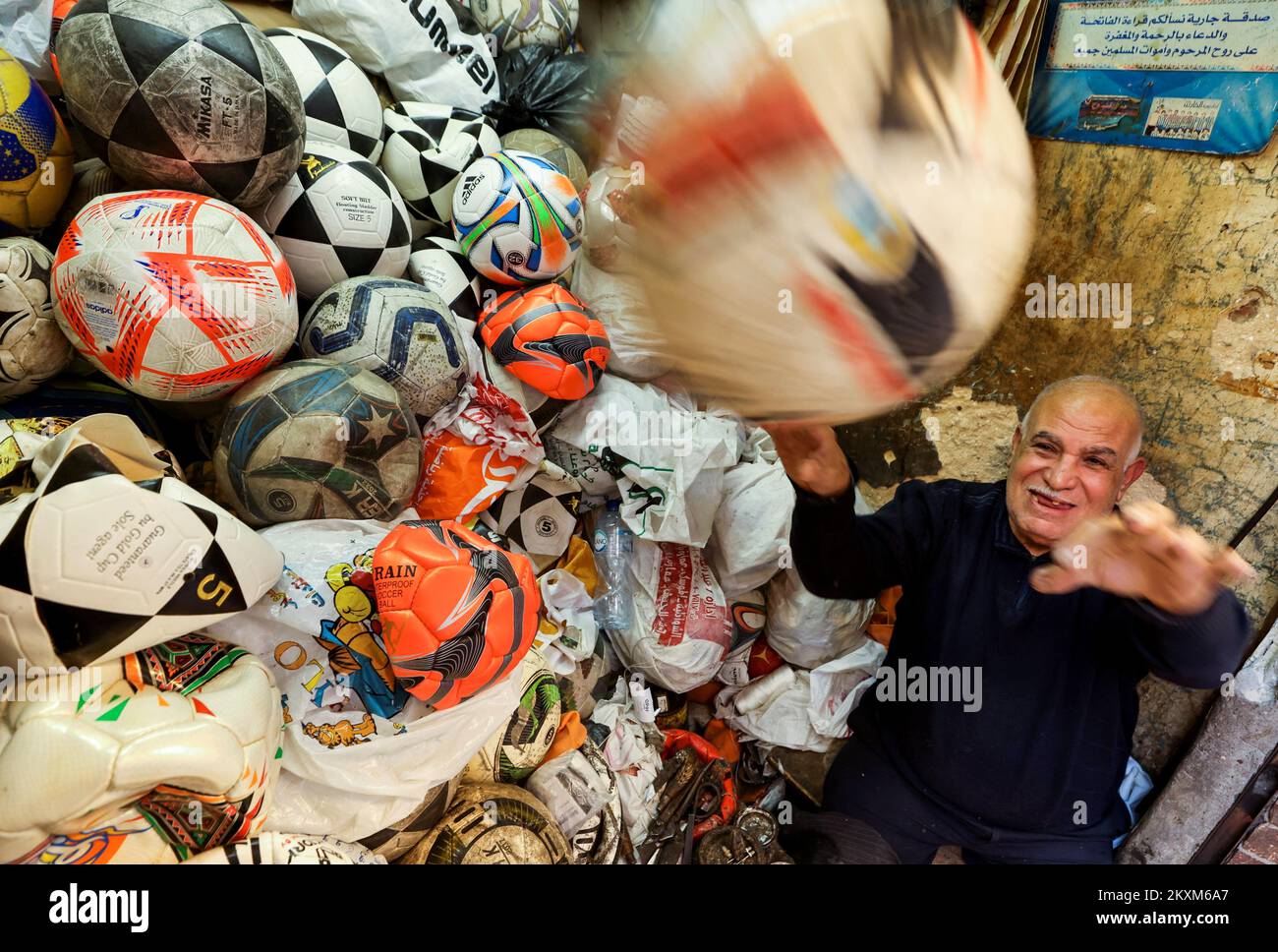 Mostafa Mahmoud, de 68 años, reacciona cuando intenta atrapar una pelota de fútbol, ha estado arreglando y fabricando pelotas desde hace 50 años, en El Cairo, Egipto, el 30 de noviembre de 2022. REUTERS/Mohamed Abd El Ghany Foto de stock