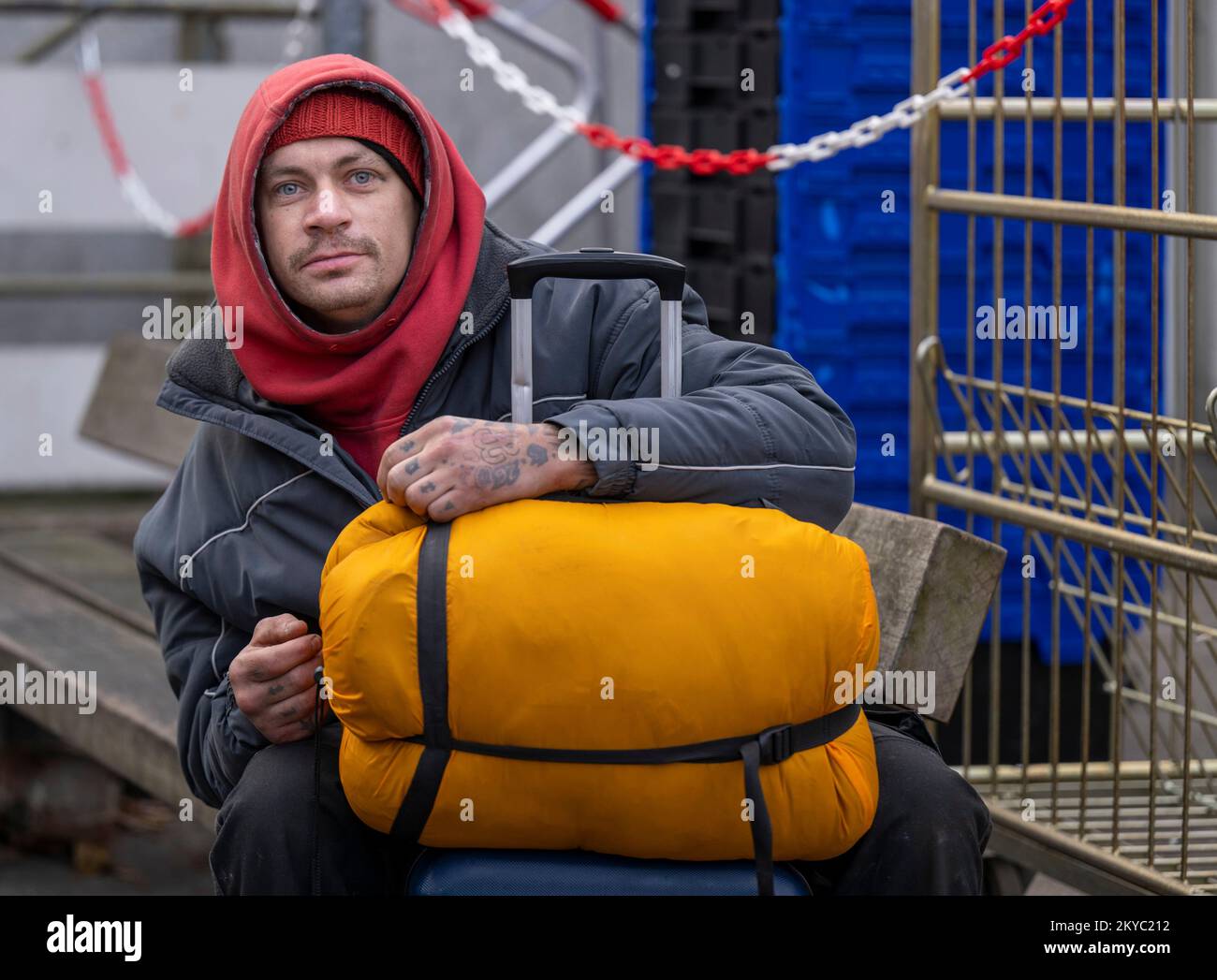 Berlín, Alemania. 28th de Nov de 2022. El hombre sin hogar de 32 años Dawid  se sienta con su maleta y saco de dormir delante de la entrada de la tienda  de