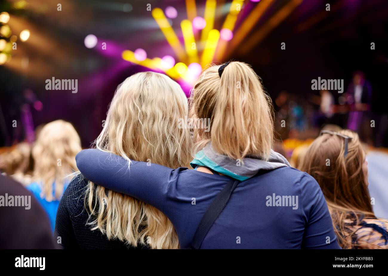 Cada ritmo los une más. Imagen trasera de dos amigos disfrutando juntos de un concierto. Foto de stock