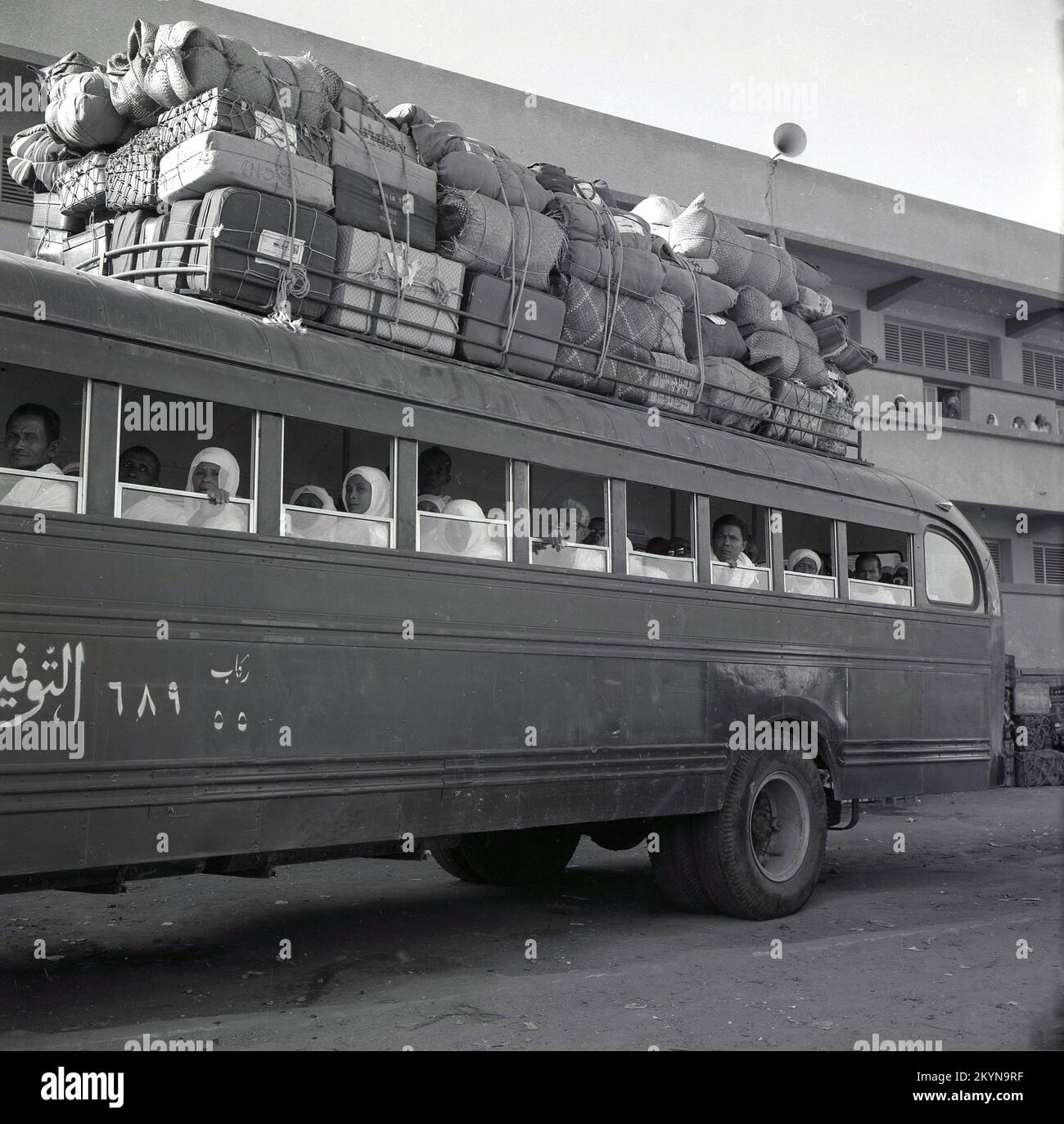 1960s, histórico, estacionado fuera de un autobús importado American International Harvester B180, con pasajeros sentados en el interior y una gran cantidad de equipaje y carga cargada en el techo, atado con cuerda, Riyadh, Arabia Saudita. Foto de stock