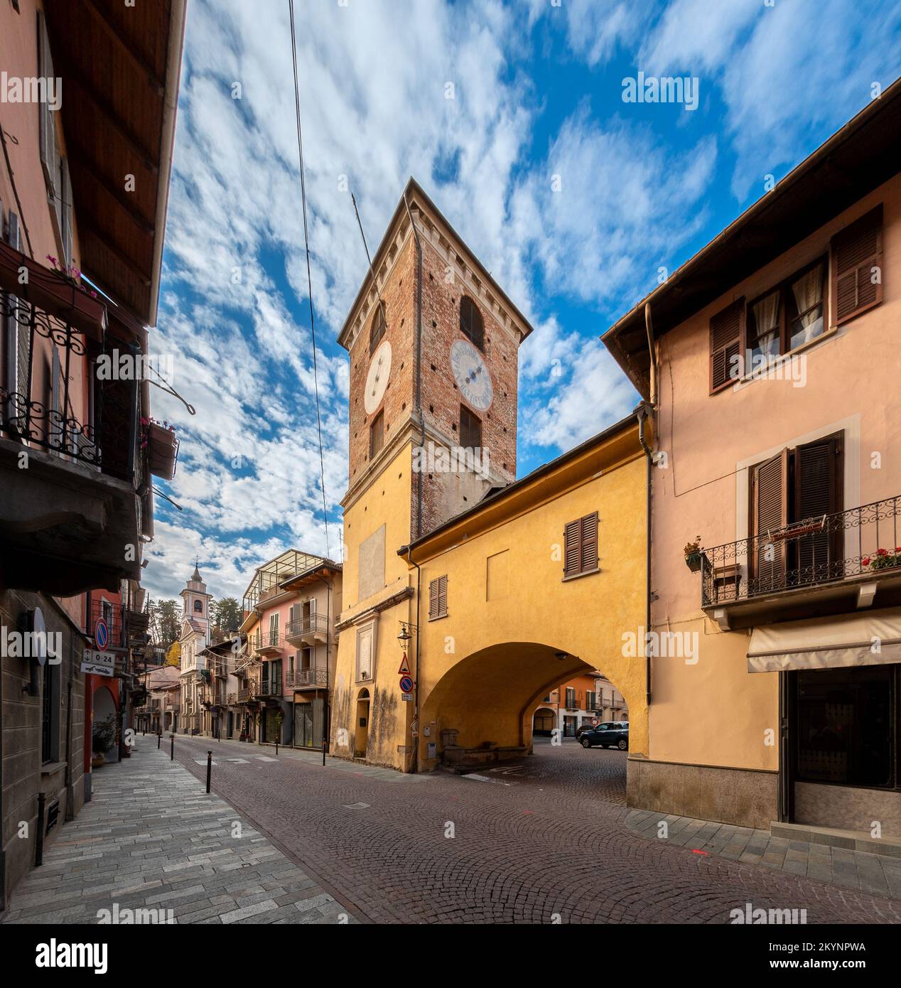 Borgo San Dalmazzo, Cuneo, Italia - 01 de diciembre de 2022: Via Roma con la torre cívica, construida en el siglo 16th, con arco para permitir el acceso a la estantería Foto de stock