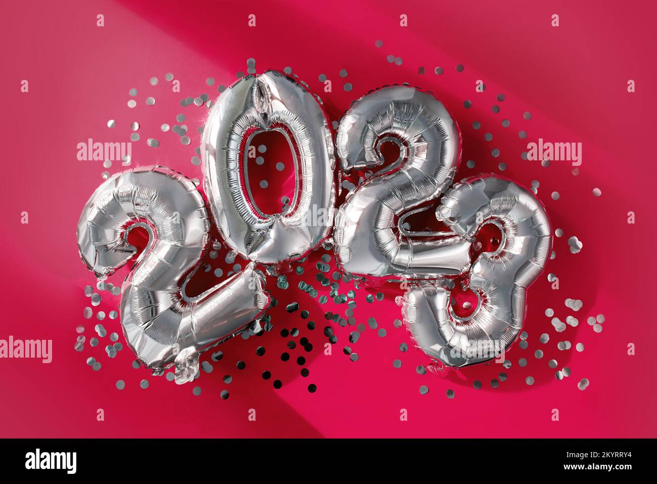 Números de plata 2023 globos de año nuevo entre confeti en la luz del sol en Viva Magenta fondo feliz fiesta de celebración de año nuevo. Saludos y felicitaciones Foto de stock