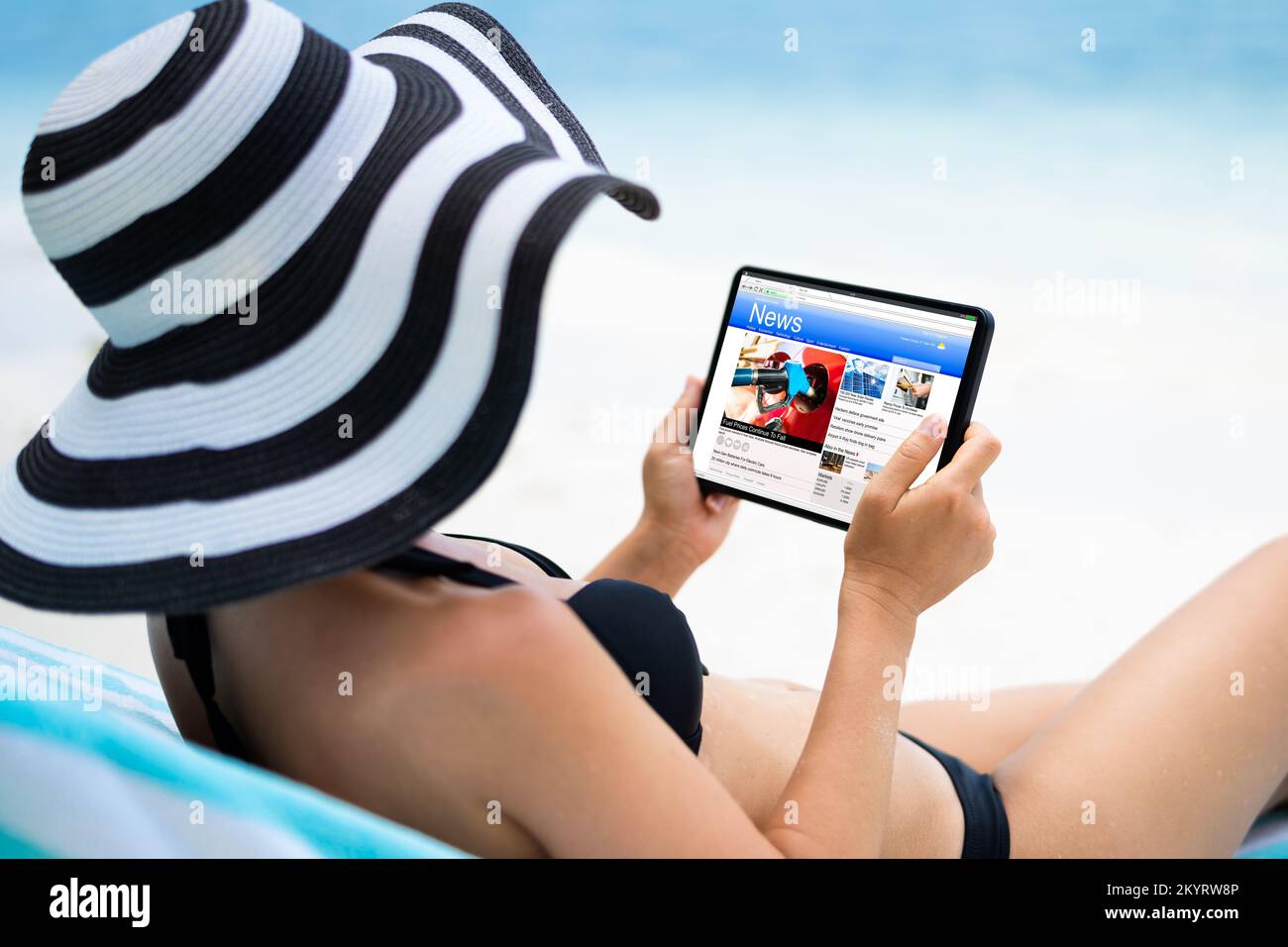 Mujer leyendo noticias en teléfono digital en la playa Foto de stock