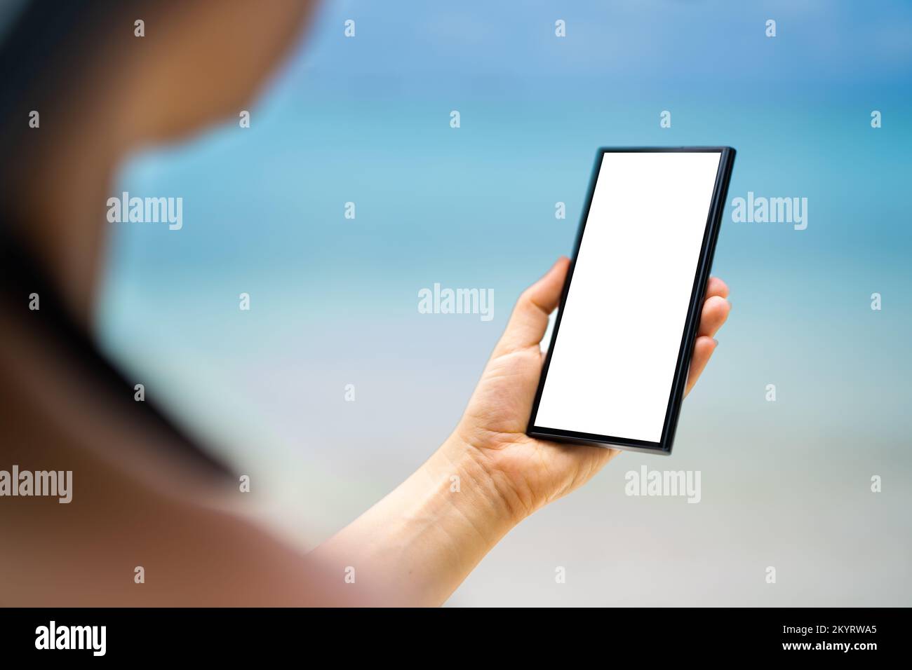 Teléfono móvil o smartphone con pantalla verde en la playa Foto de stock