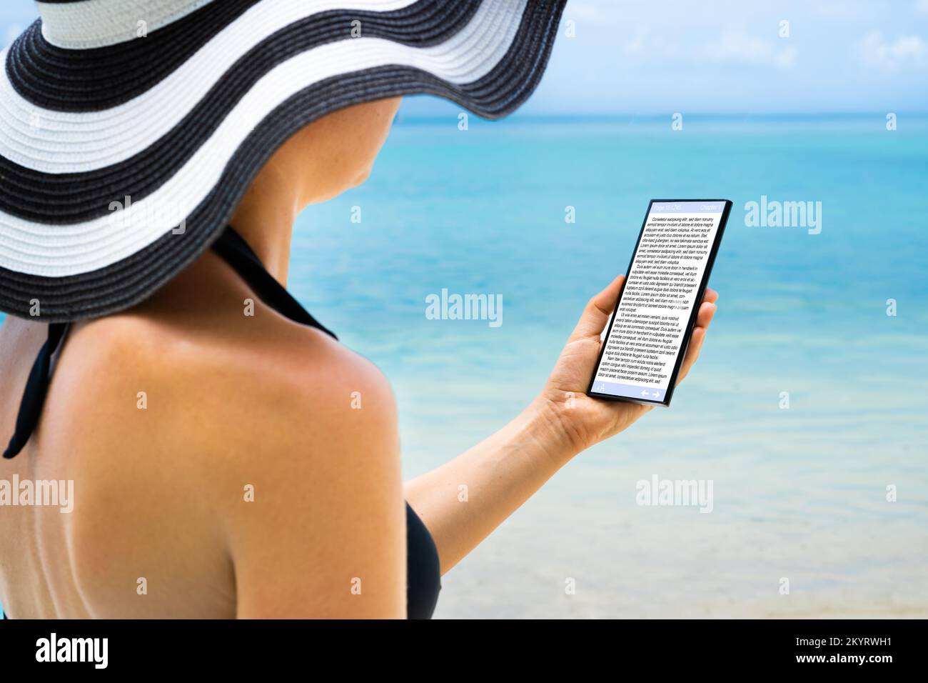 Mujer leyendo E-libro en la tableta en la playa Foto de stock