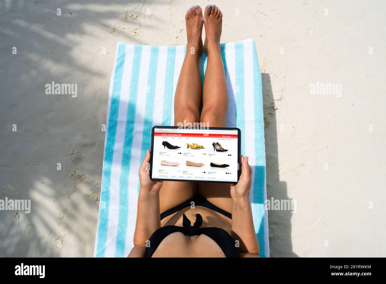 Mujer de compras para zapatos en la tienda web en la playa Foto de stock