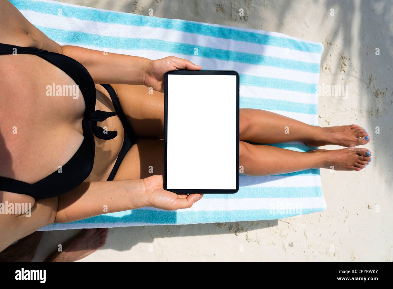 Mujer usando la tableta mientras se relaja en silla de playa Foto de stock