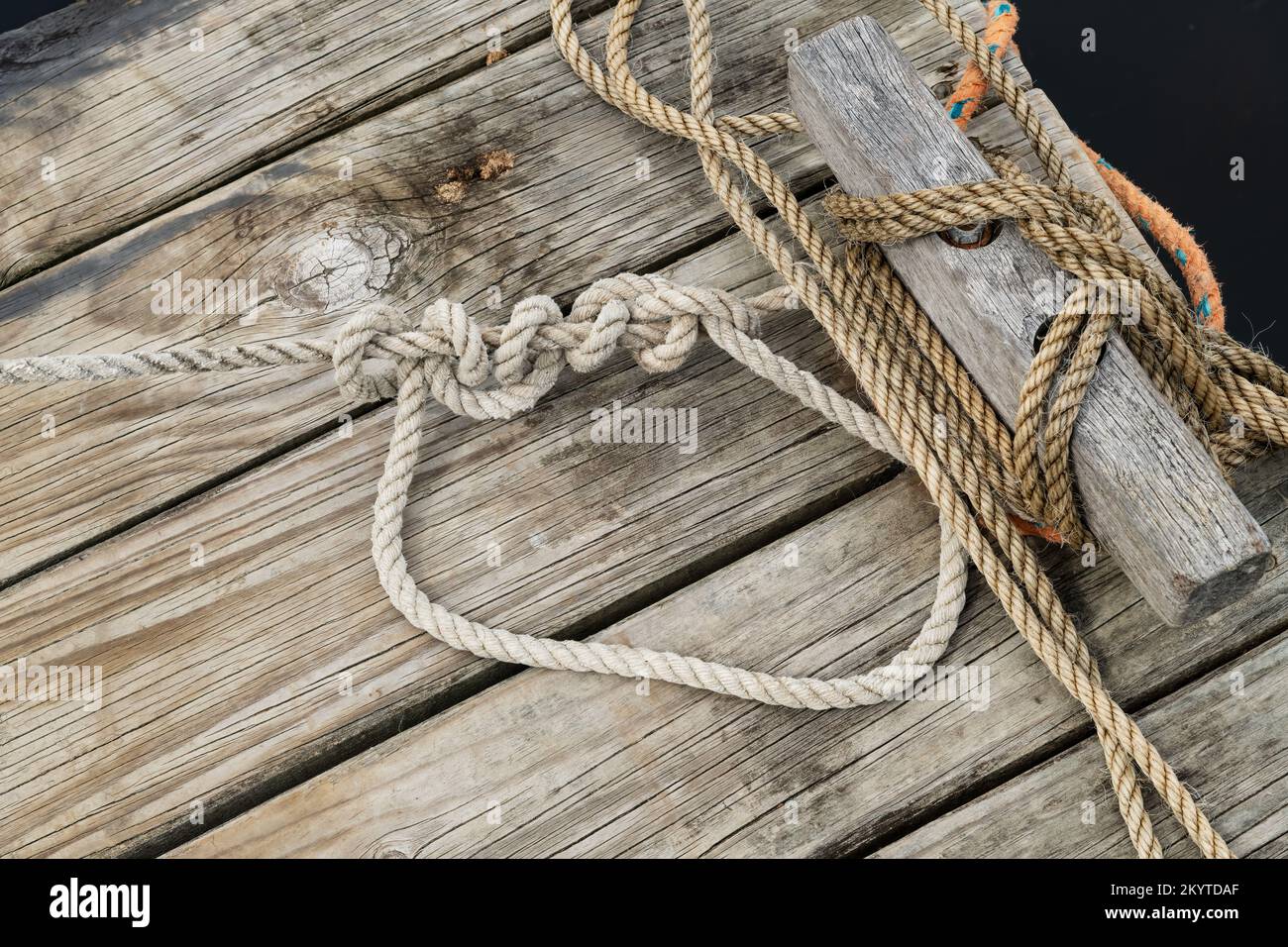 Un viejo embarcadero de madera con cuerdas de los barcos unidos al punto de amarre, Foto de stock