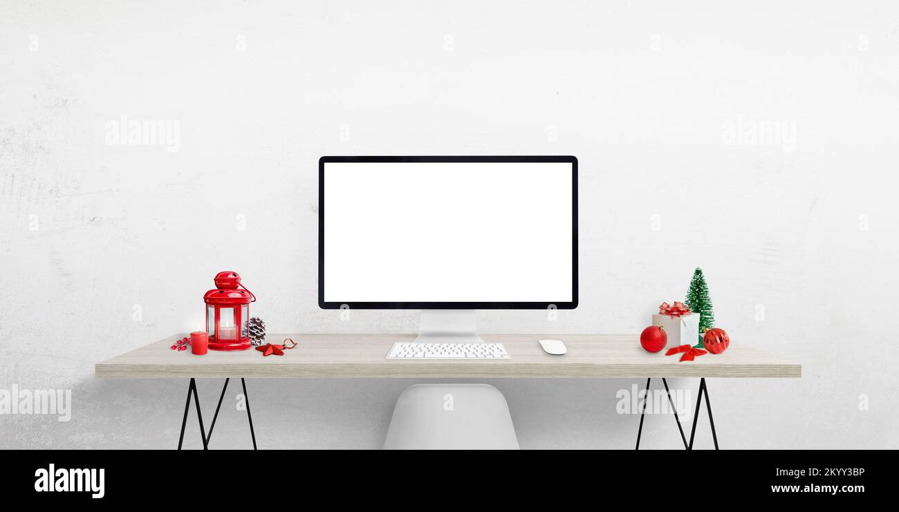 Pantalla de ordenador en blanco en el escritorio rodeado de adornos navideños. Pantalla aislada para texto de bienvenida de Navidad, página web o presentación de productos Foto de stock