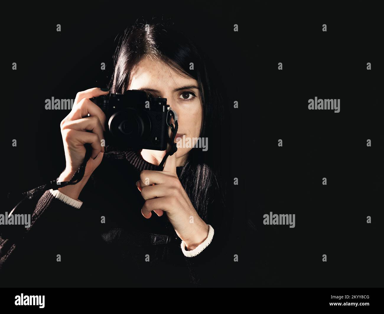 mujer fotógrafa cámara de primer plano fondo negro Foto de stock