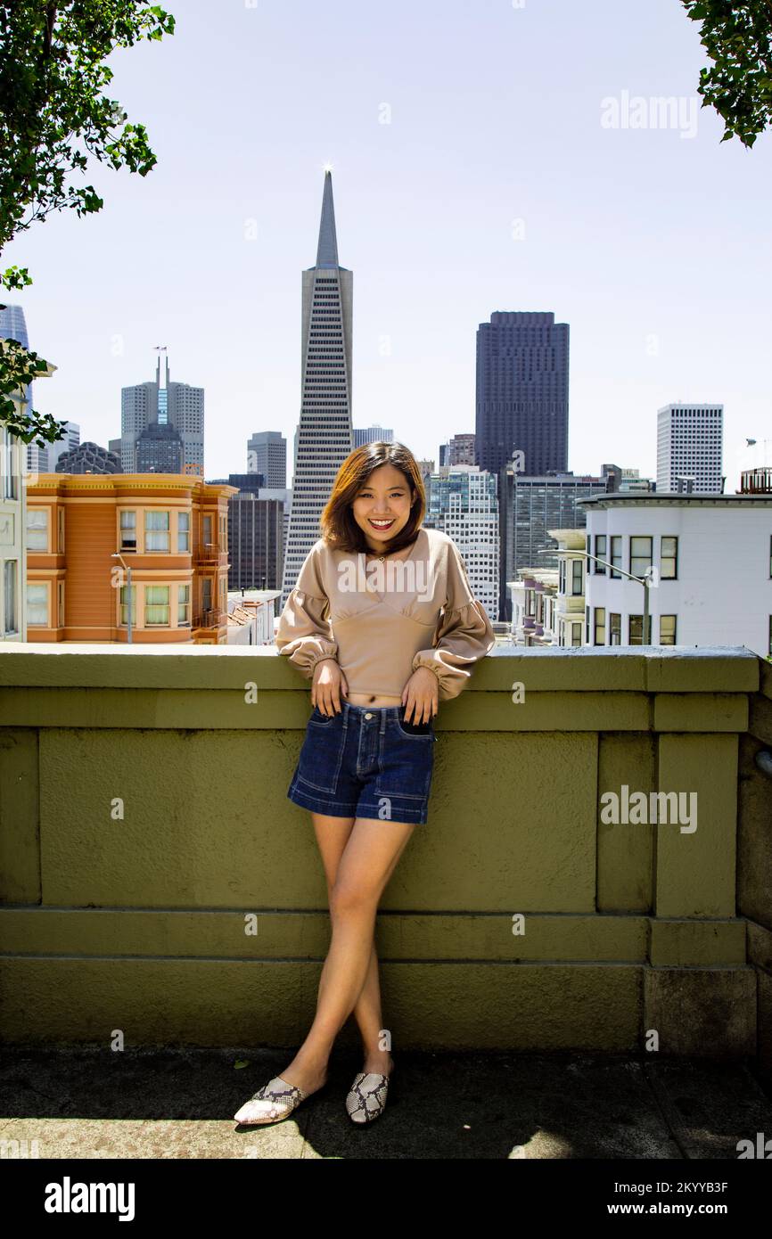 Retrato de cuerpo completo de una joven sonriente de pie con el horizonte de San Francisco en el fondo Foto de stock